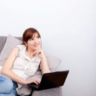 Junge Frau entspannt auf der Couch mit Laptop – Effektives und flexibles Online-Kroatischlernen.